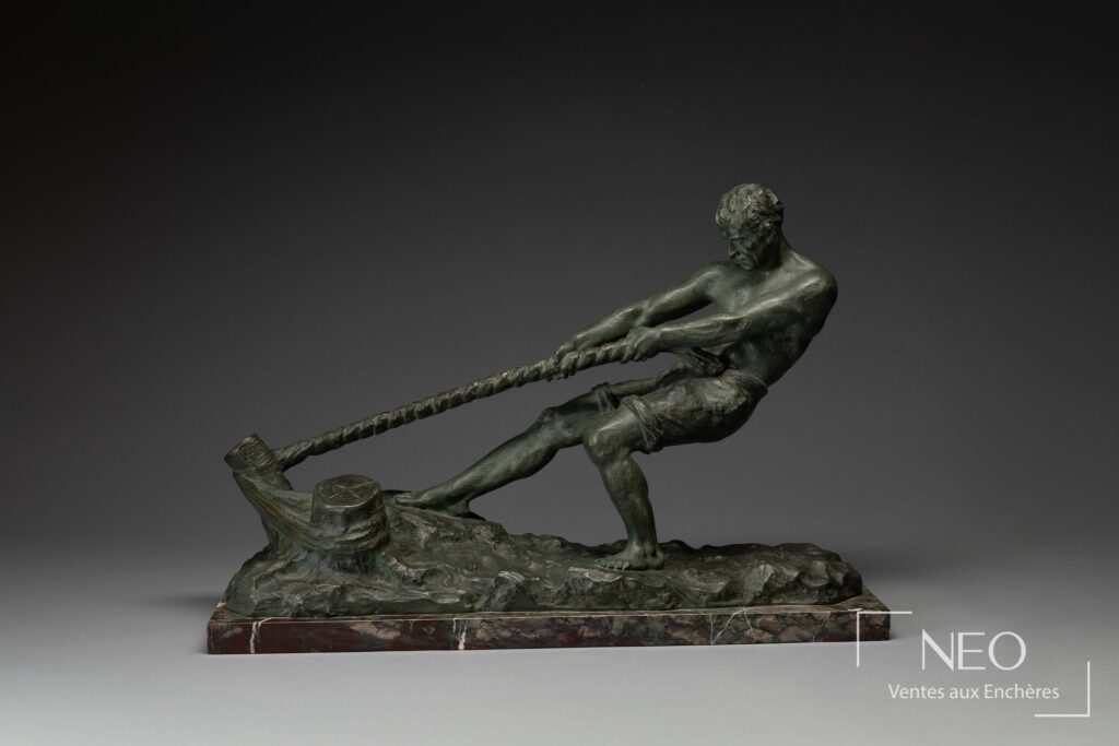 Sculpture en bronze patiné vert montrant un haleur tirant une corde sur socle en marbre.