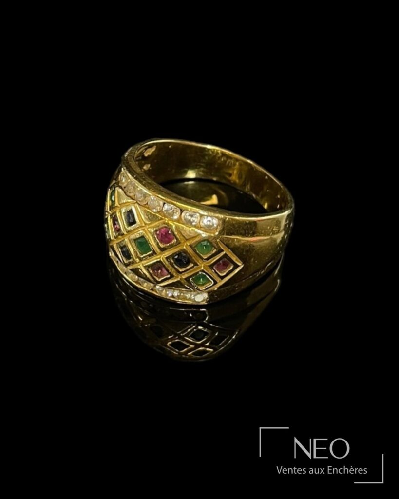 Bague arlequin en or jaune ornée de pierres multicolores sur fond noir