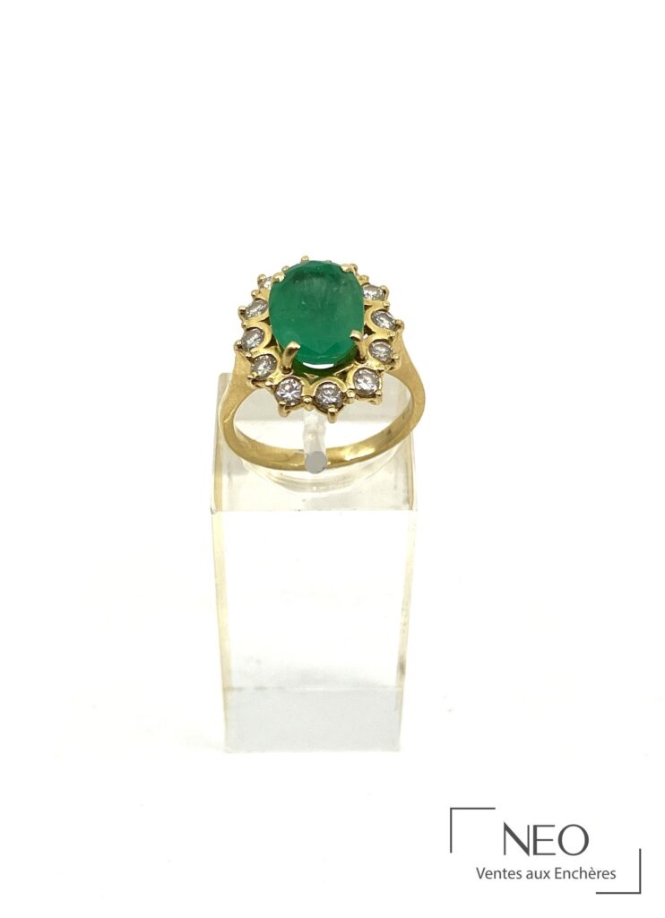 Bague en or jaune sertie d’une émeraude ovale entourée de diamants