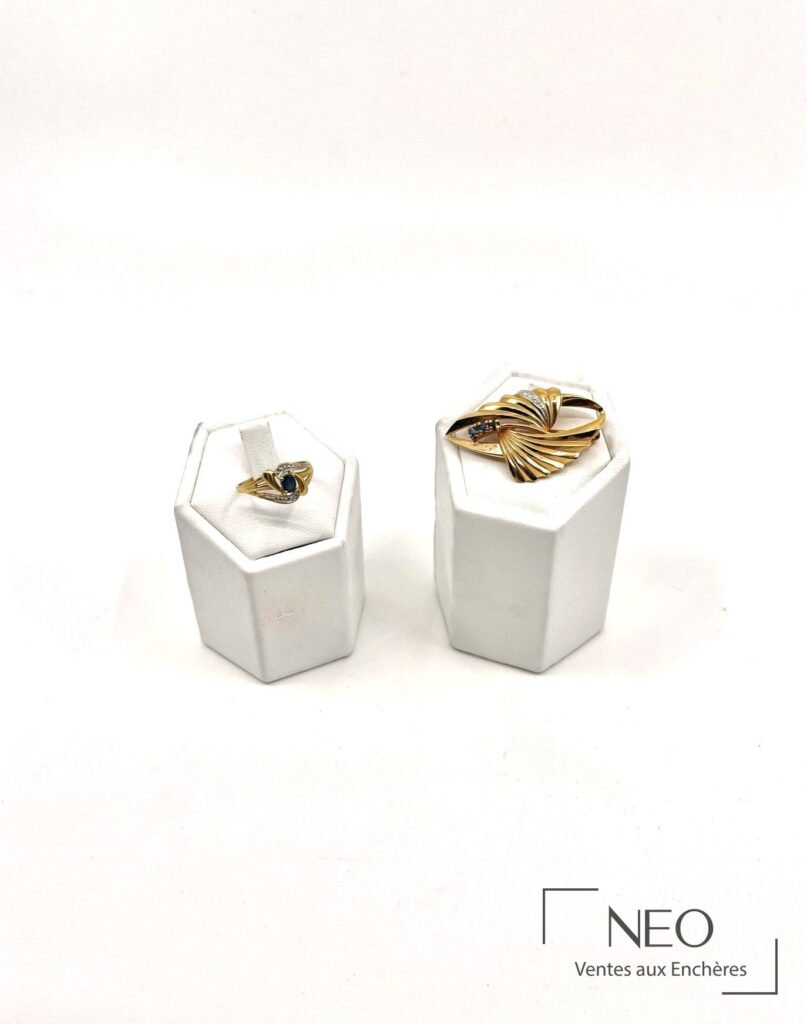 Bague en or jaune et broche assortie présentées sur supports blancs