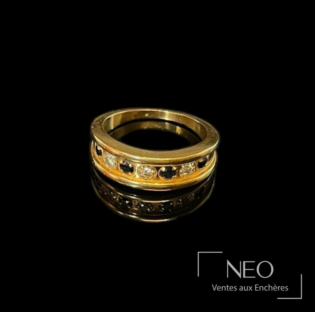 Bague jarretière en or jaune avec ligne de saphirs et diamants sur fond noir