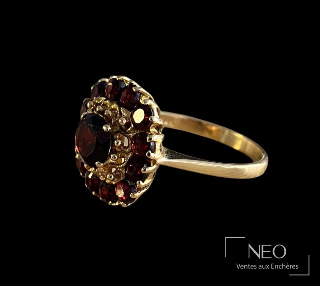 Bague marguerite en or jaune sertie de pierres rouges sur fond noir