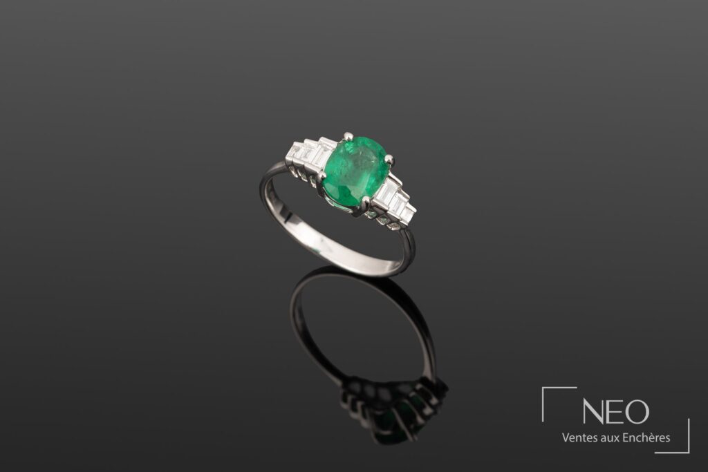 Bague en or blanc avec émeraude ovale et diamants baguette sur fond gris