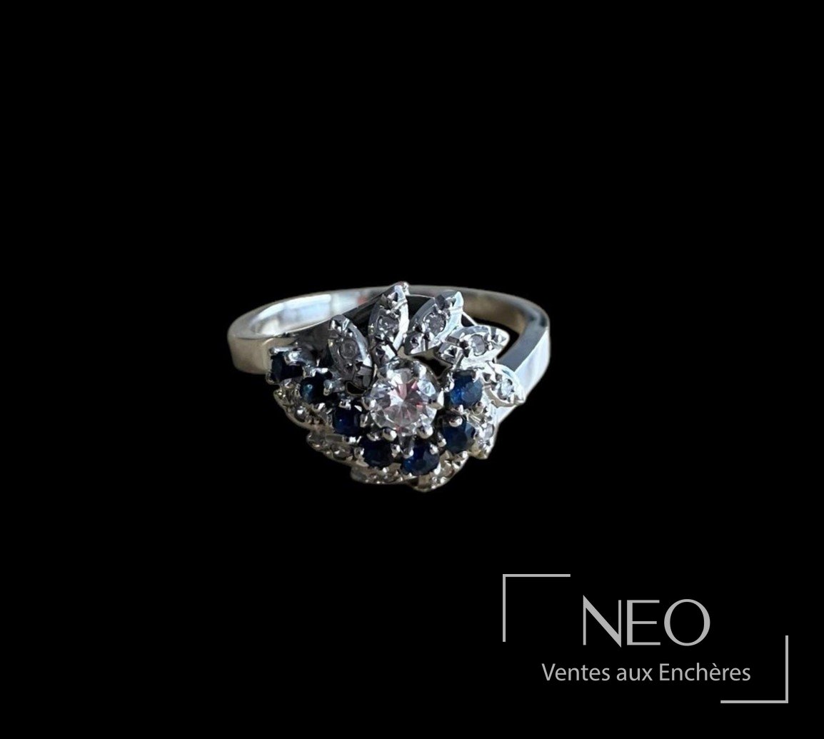 Bague en or gris avec plateau floral serti d’un diamant central et de pierres bleues