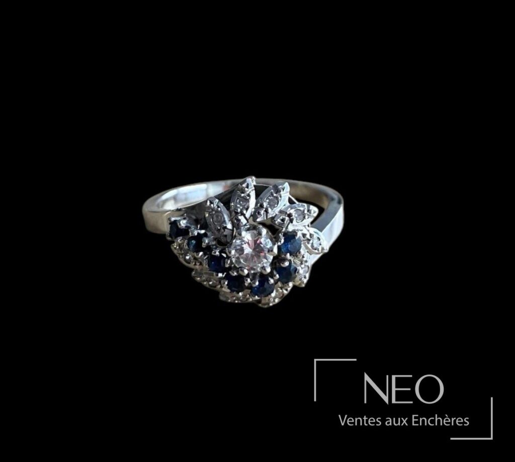 Bague en or gris sertie d’un diamant central et de pierres bleues et blanches