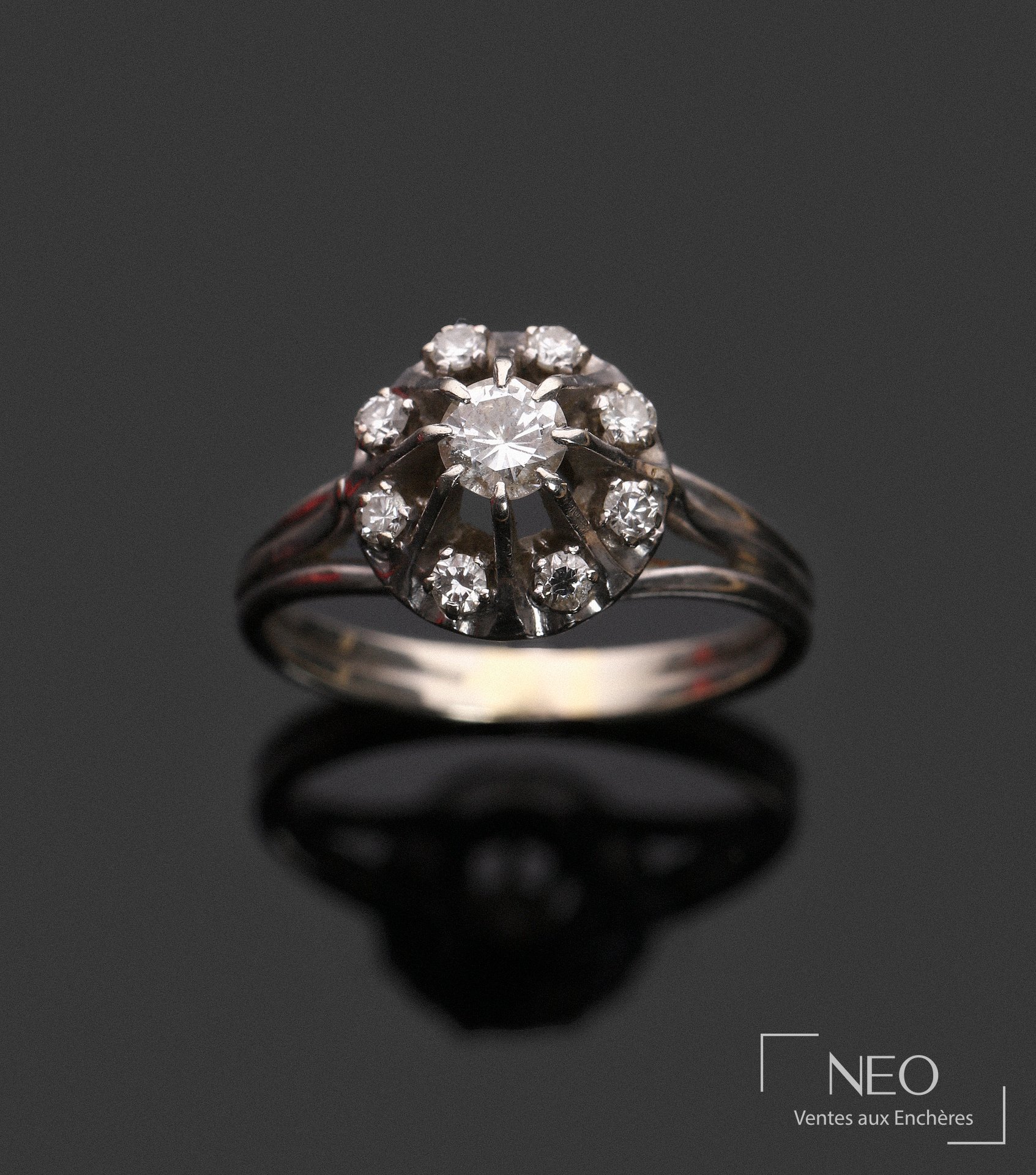 Bague en or gris 18 carats centrée d’un diamant et entourée de petits diamants