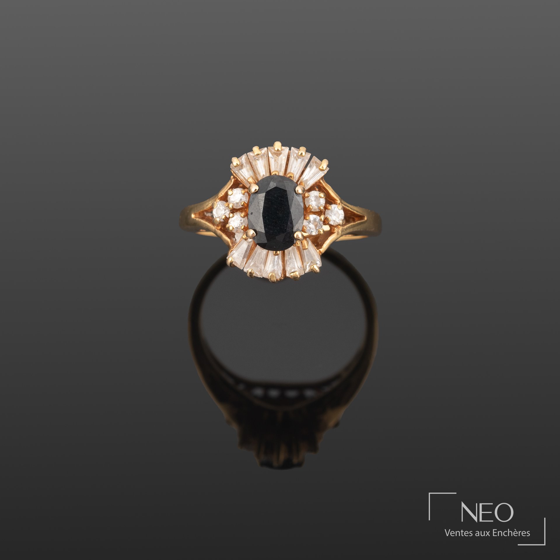 Bague en or jaune sertie d'une pierre bleue facettée entourée de pierres blanches