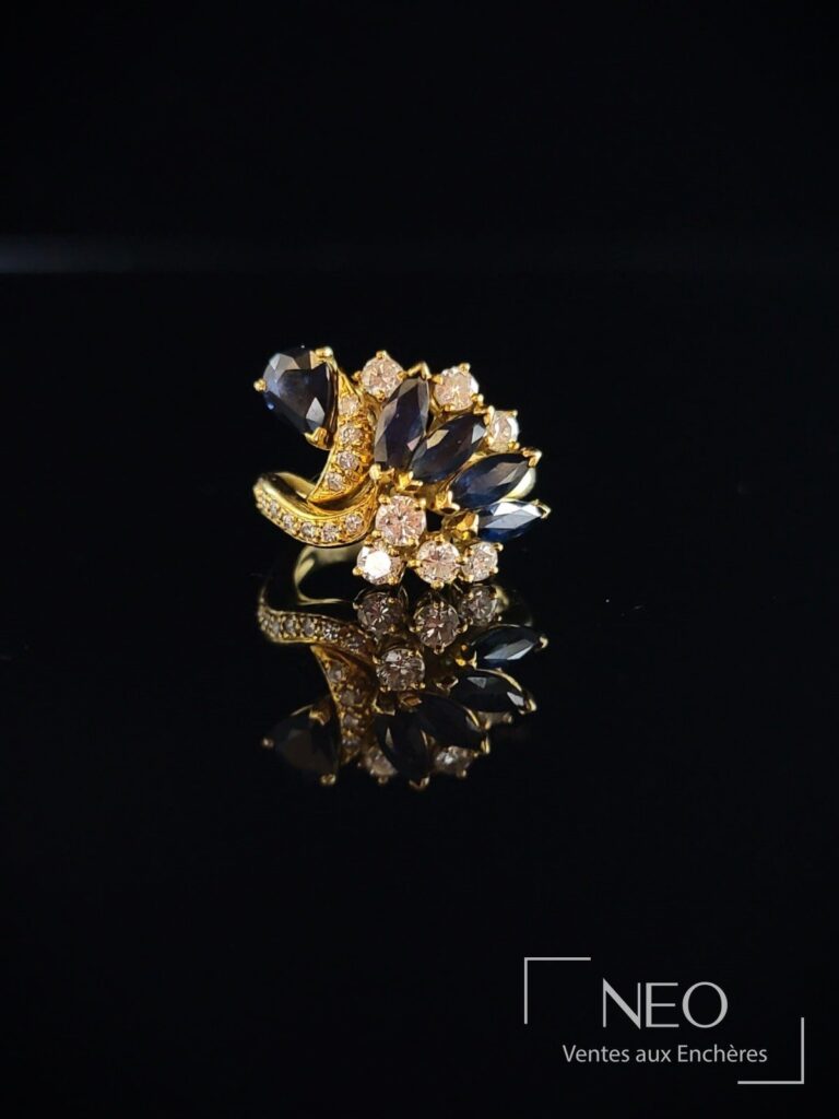 Bague en or jaune sertie de diamants et de pierres bleues sur fond noir