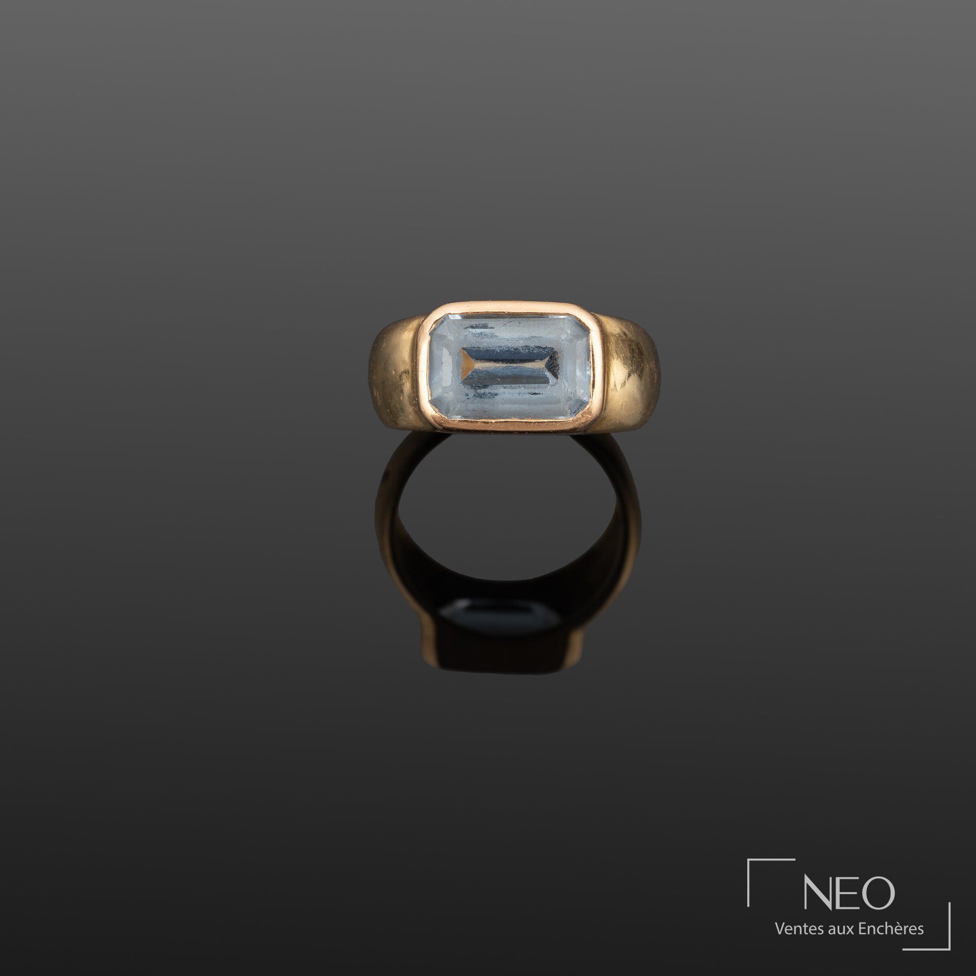 Bague en or jaune 18K centrée d’une pierre bleue taille émeraude