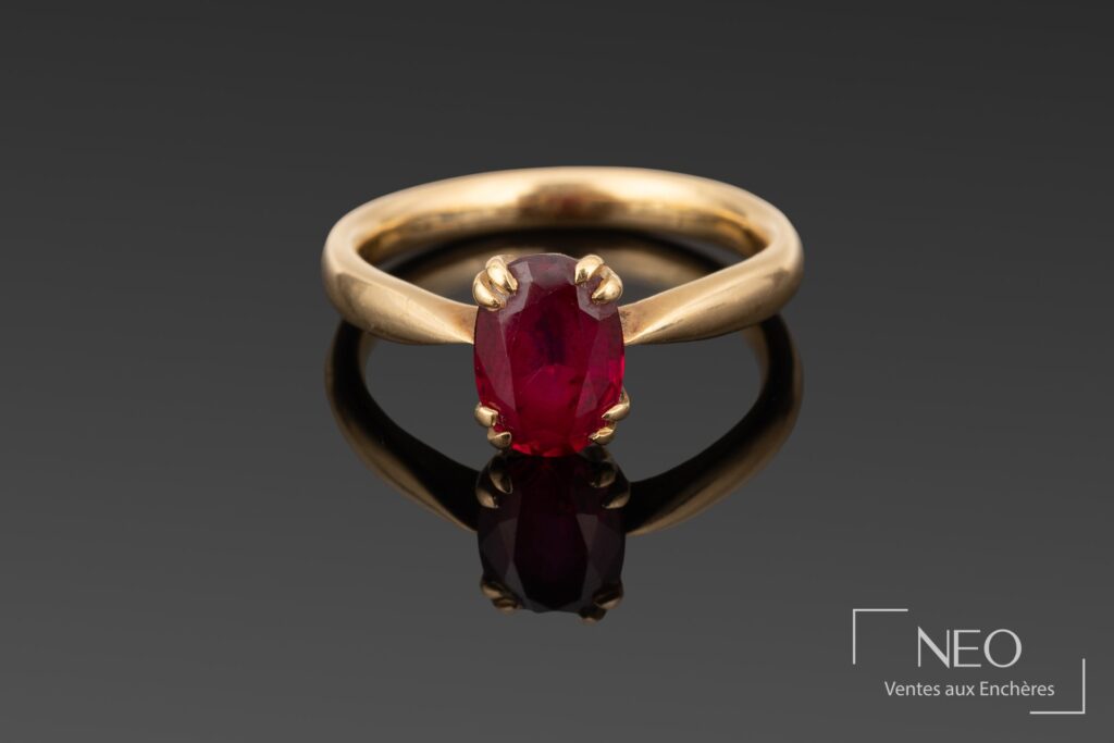 Bague en or jaune sertie d'un rubis ovale rouge sur fond gris