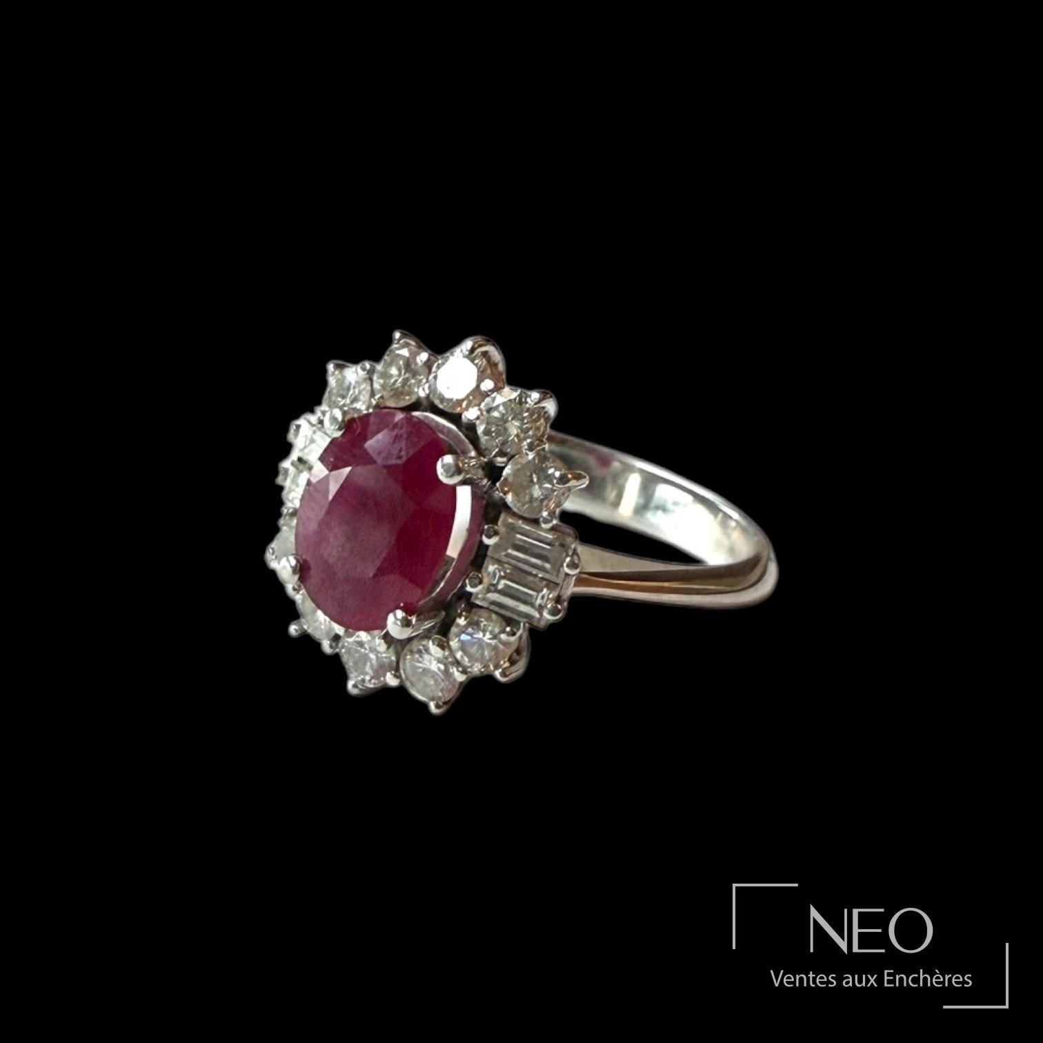 Bague en or blanc sertie d’un rubis ovale entouré de diamants sur fond noir