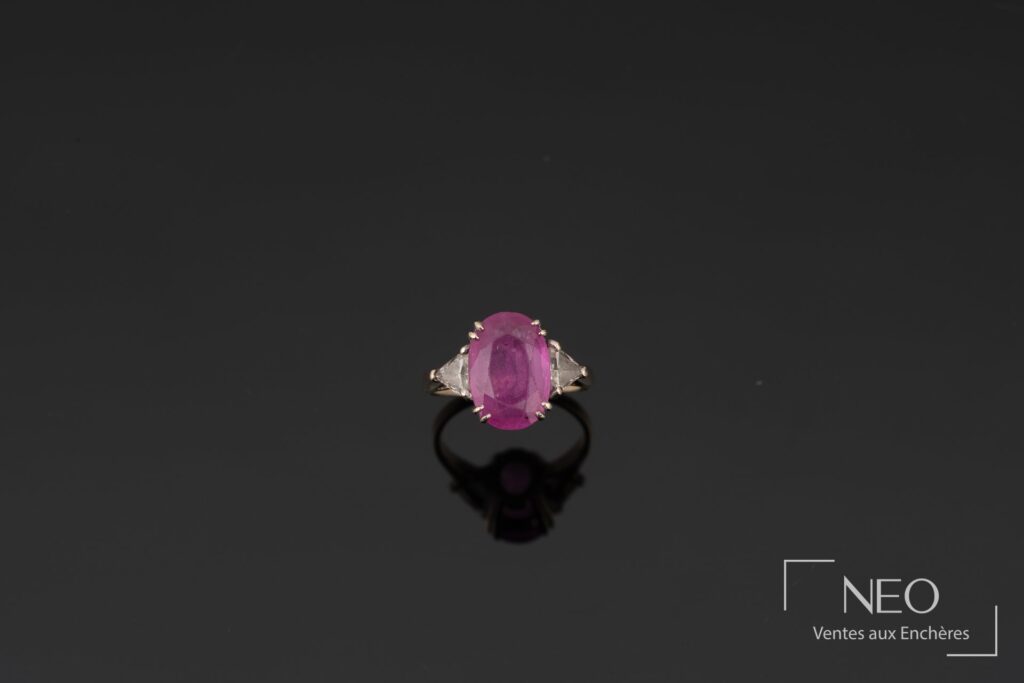 Bague en or blanc sertie d’un saphir rose ovale avec deux diamants triangulaires