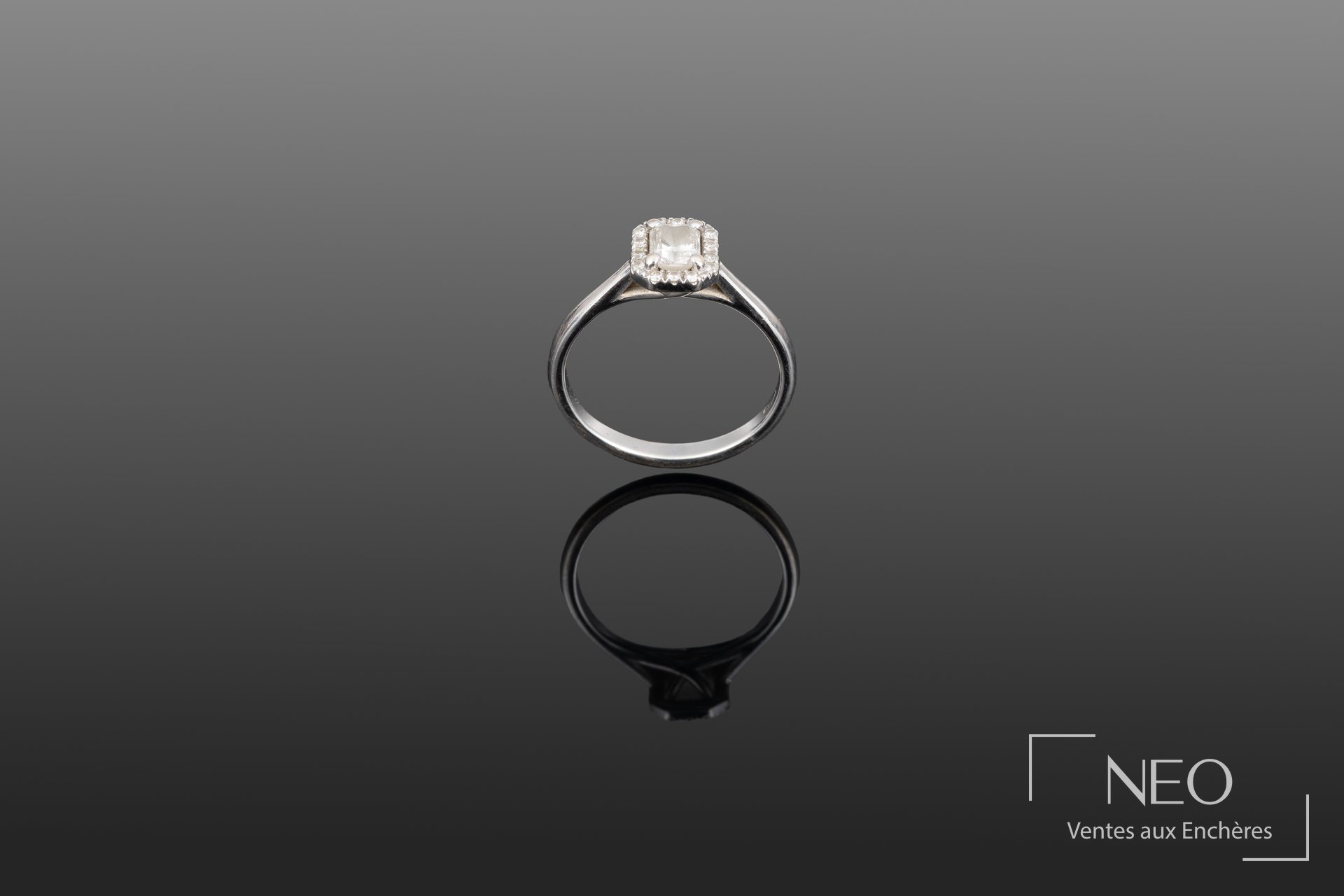 Bague solitaire en or gris avec diamant central et entourage de petits diamants