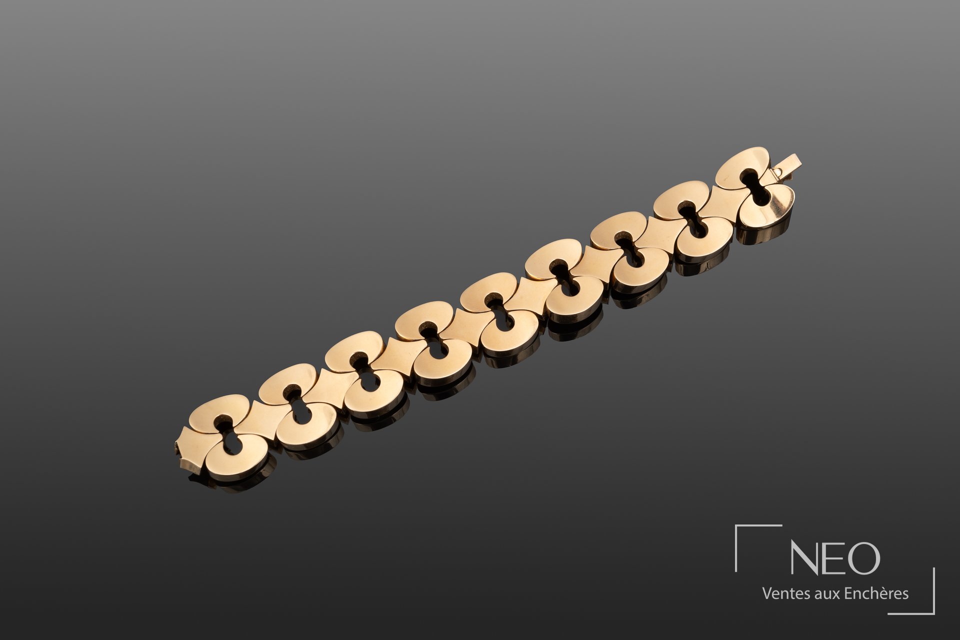 Bracelet en or jaune à neuf maillons ajourés sur fond gris