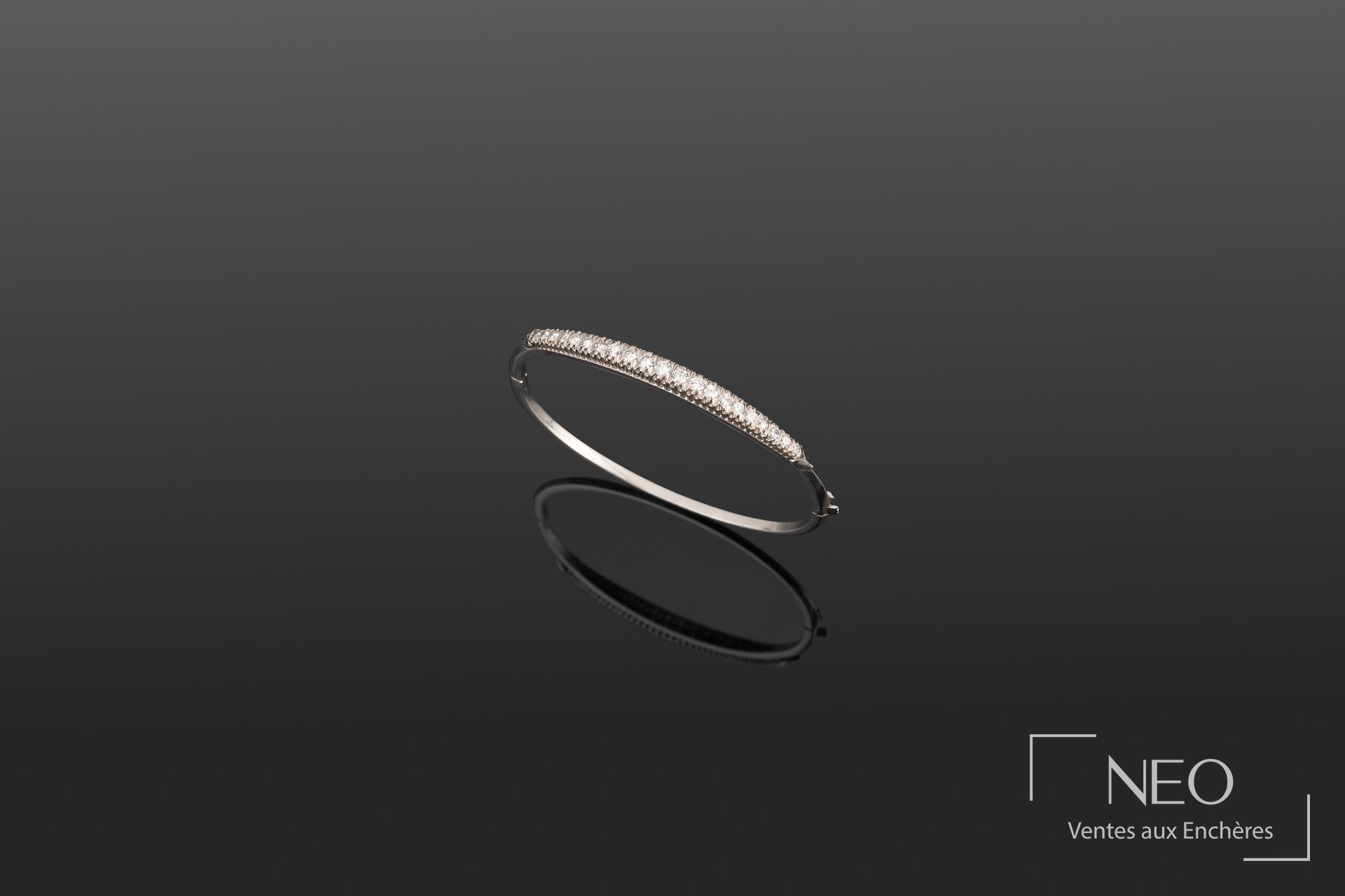 Bracelet rigide ouvrant en or blanc serti d’une ligne de diamants sur fond sombre