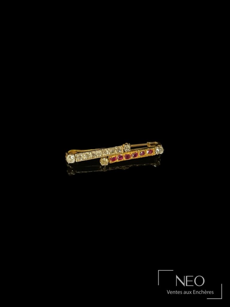 Broche barrette en or jaune et platine ornée de diamants et de pierres rouges sur fond noir