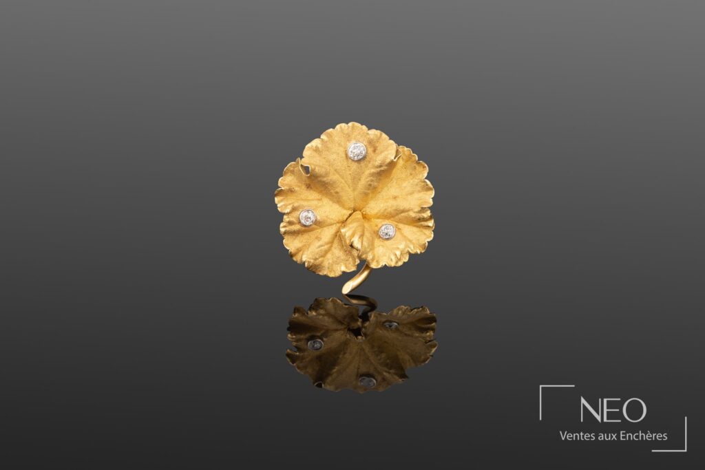 Broche feuille en or jaune et gris ornée de trois diamants sur fond gris