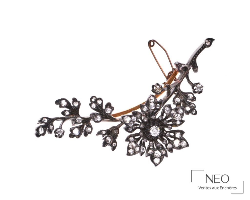 Broche fleur ajourée sertie de diamants sur fond blanc