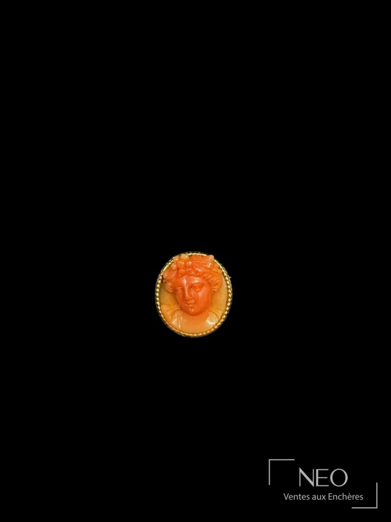 Broche ronde en or jaune ornée d’un visage féminin en corail rouge