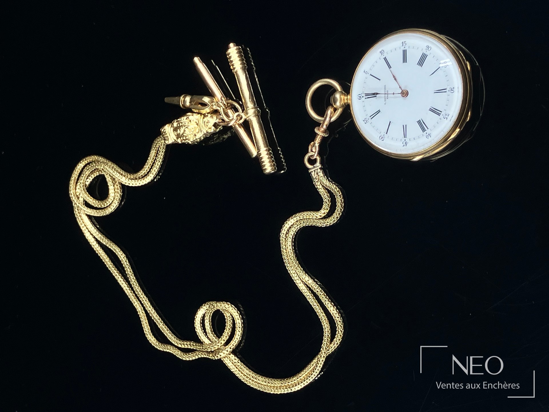 Montre à gousset en or jaune avec chaîne giletière et clé de remontage sur fond noir