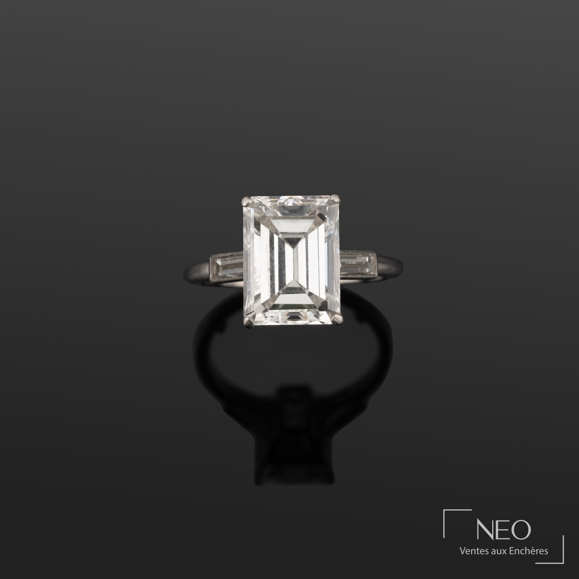 Bague Cartier en platine avec diamant taille émeraude et deux diamants baguettes
