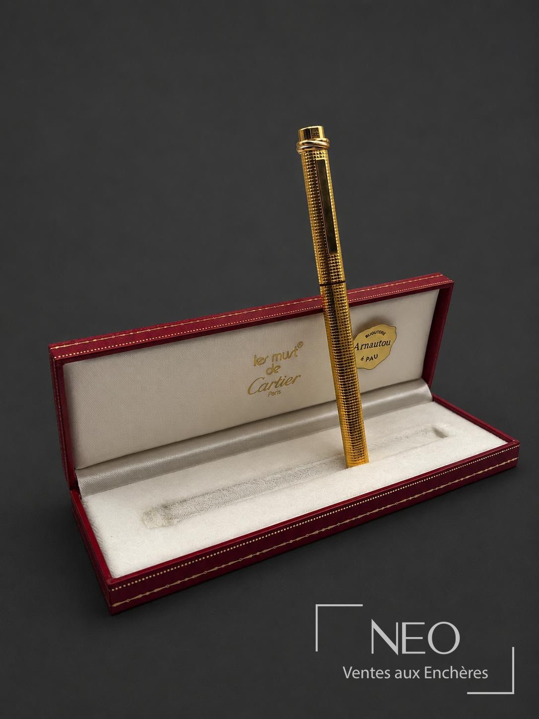 Stylo-bille Cartier Must Trinity en or plaqué présenté dans son écrin rouge ouvert