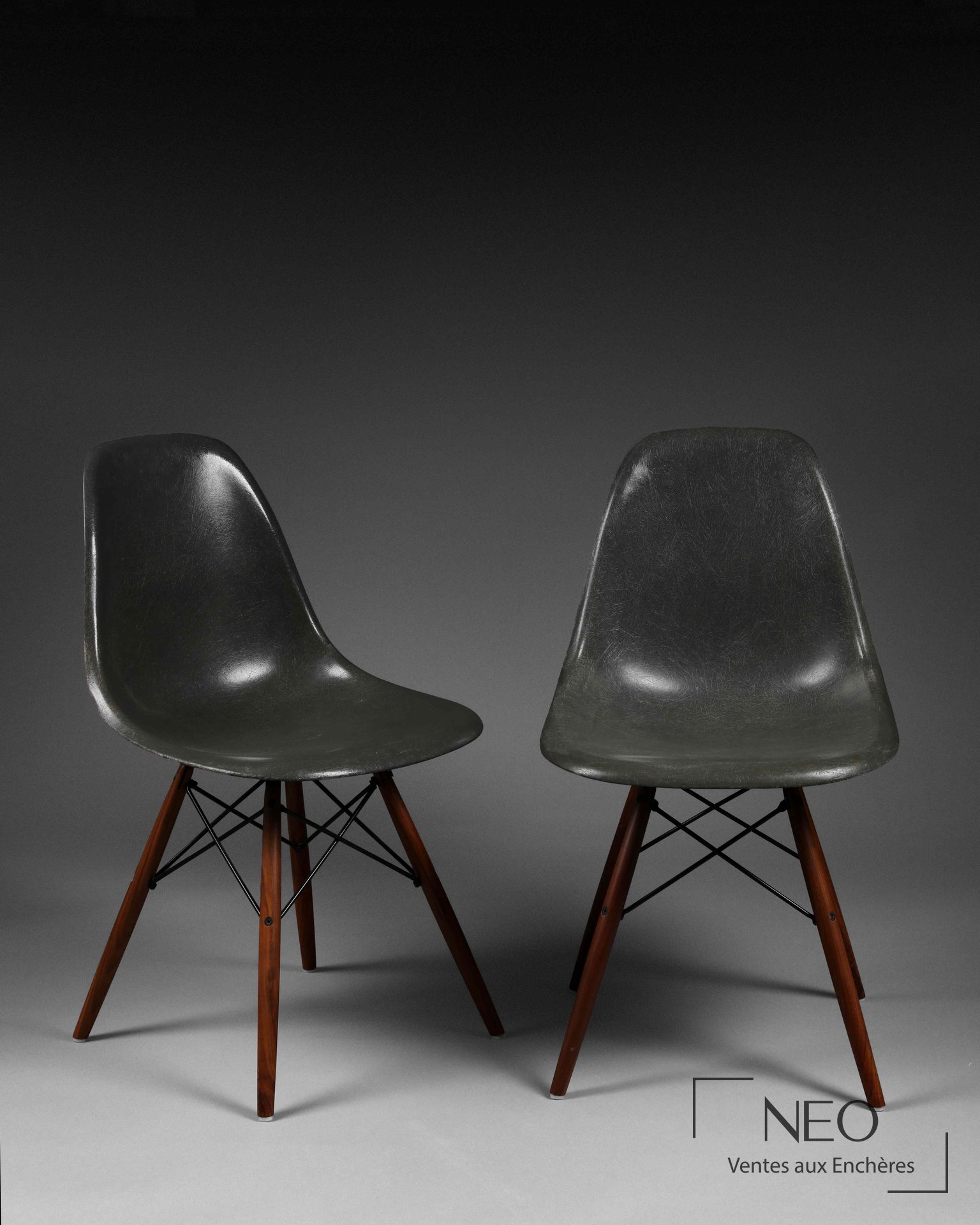 Deux chaises DSW Eames en fibre de verre gris avec piétement en bois.