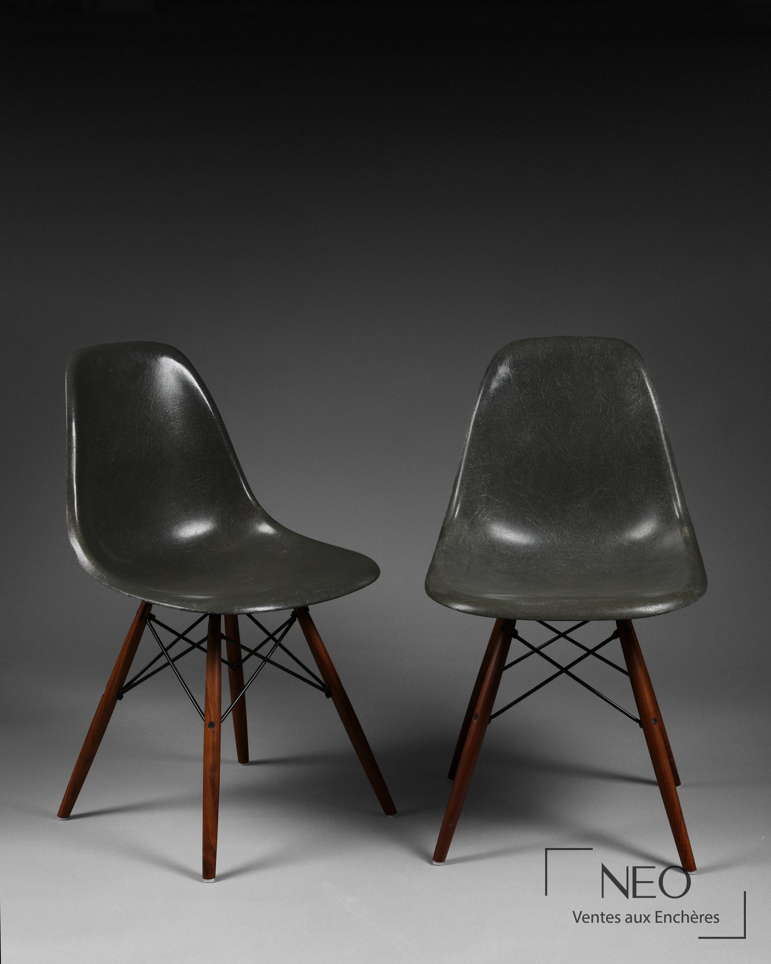 Deux chaises DSW en fibres de verre gris avec piétement en bois et croisillons noirs.