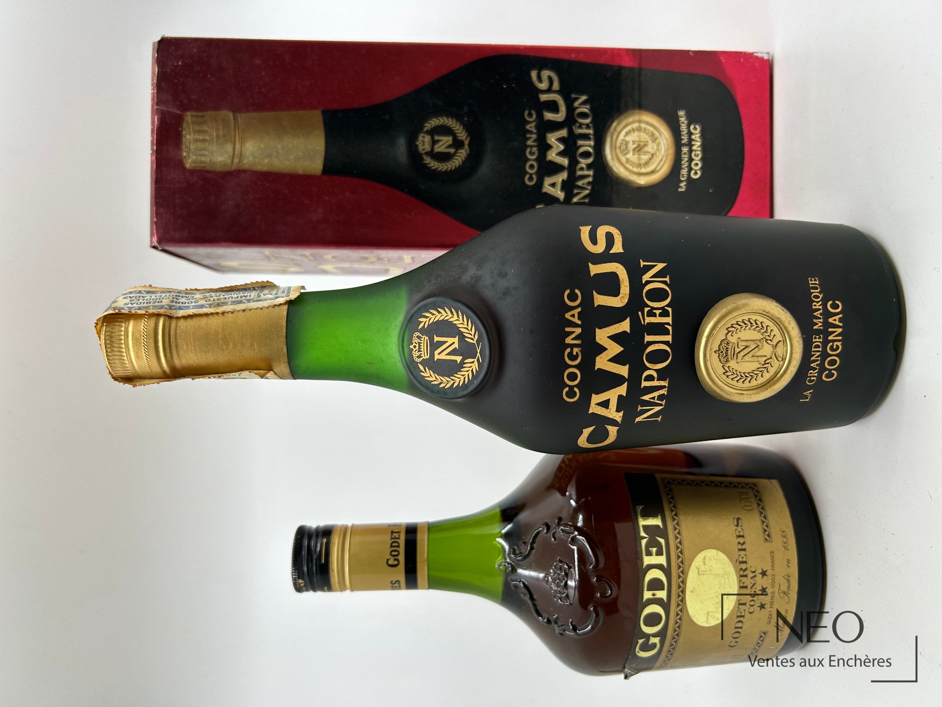 Lot de deux bouteilles de cognac avec une boîte Camus visible derrière