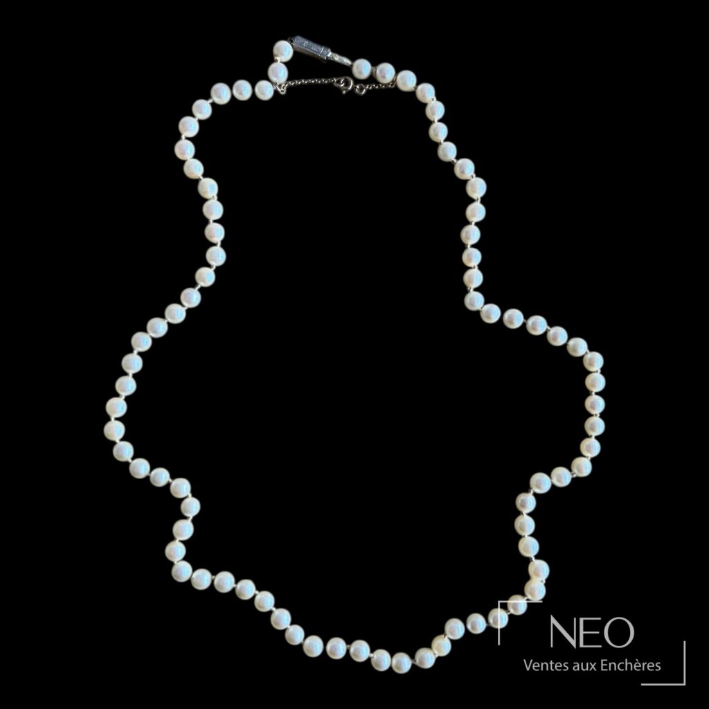 Collier de perles de culture blanches sur fond noir avec fermoir visible