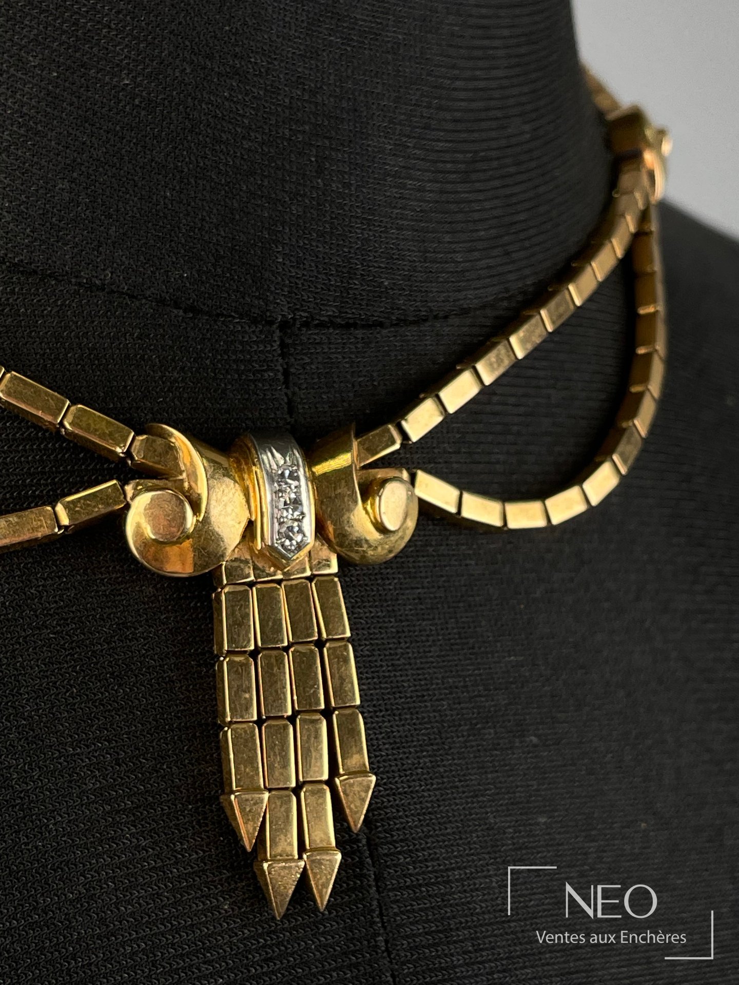 Collier en or jaune à pendentif central en forme de nœud stylisé avec trois diamants.