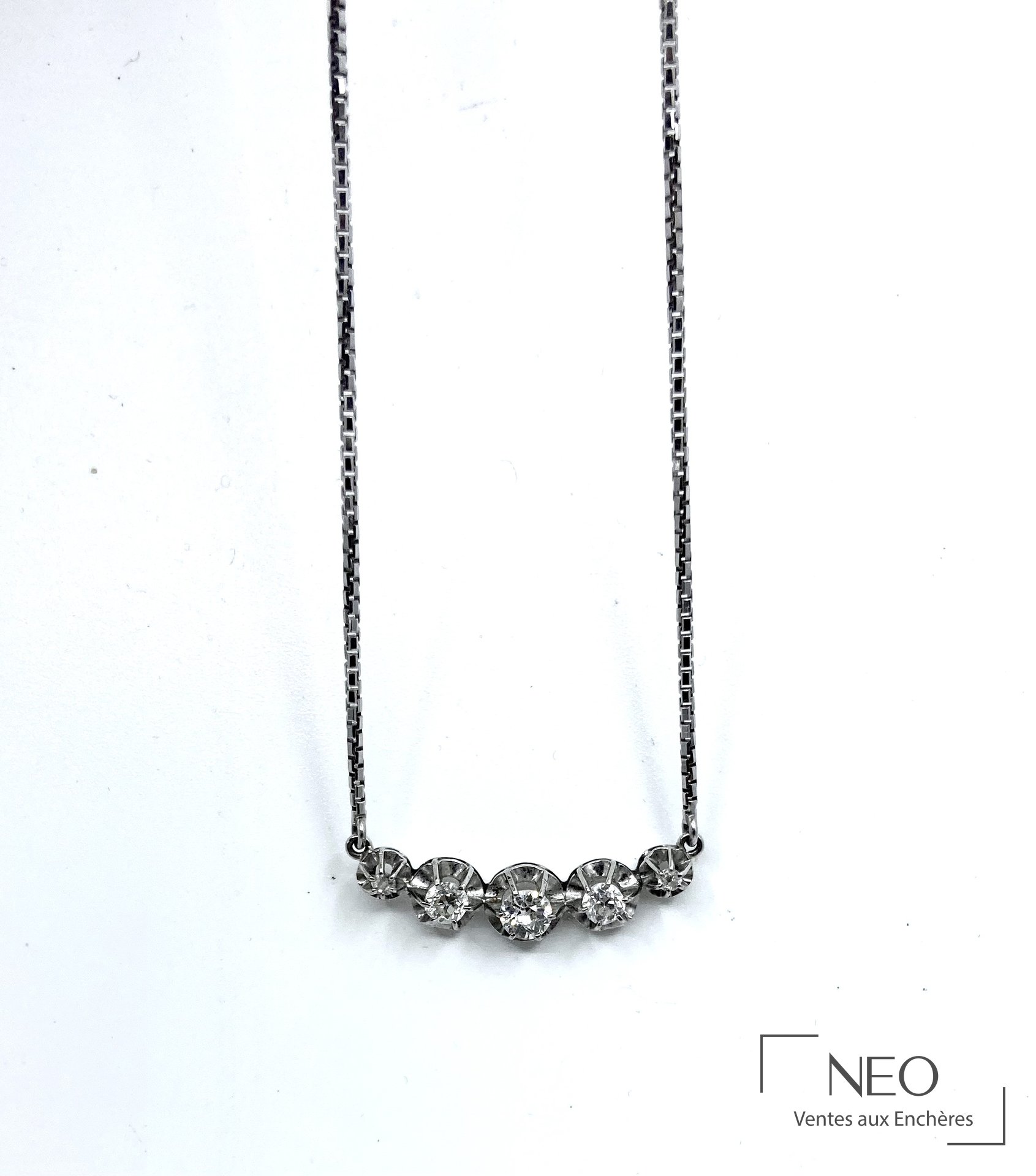 Collier en or gris avec cinq diamants sertis en ligne sur fond blanc