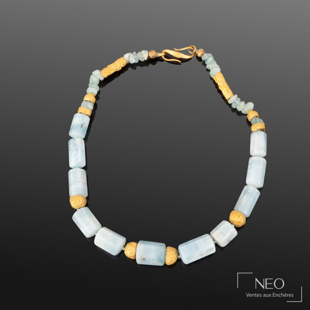 Collier ras-de-cou composé de perles bleues et d'éléments dorés sur fond sombre