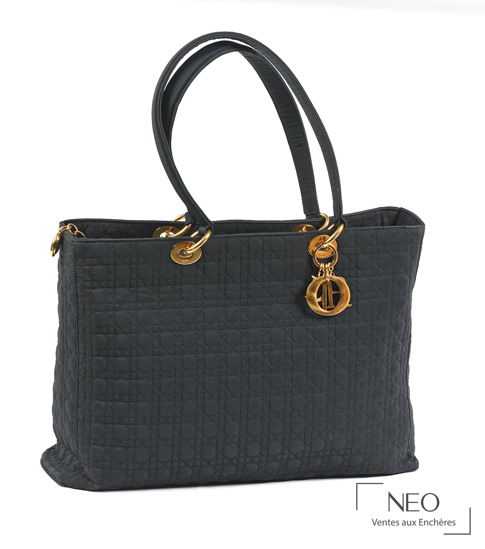 Sac Lady Dior noir en nylon tissé avec anses rigides et breloques dorées.