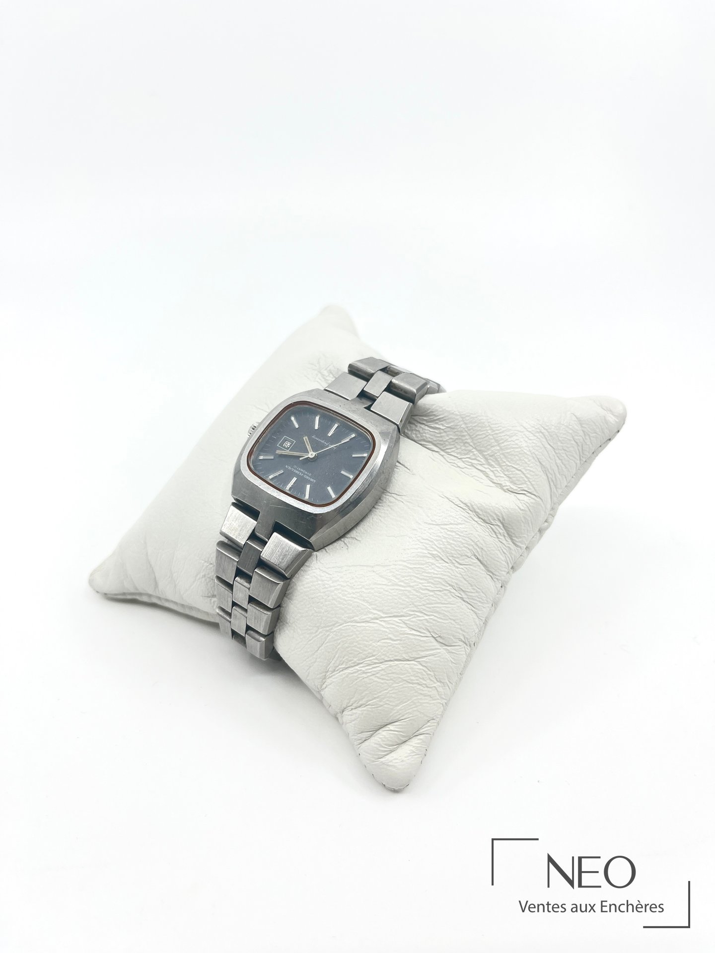 Montre bracelet GIRARD-PEREGAUX en acier posée de biais sur coussin blanc