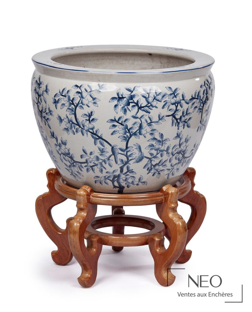 Grand vase en porcelaine bleue et blanche posé sur un socle en bois