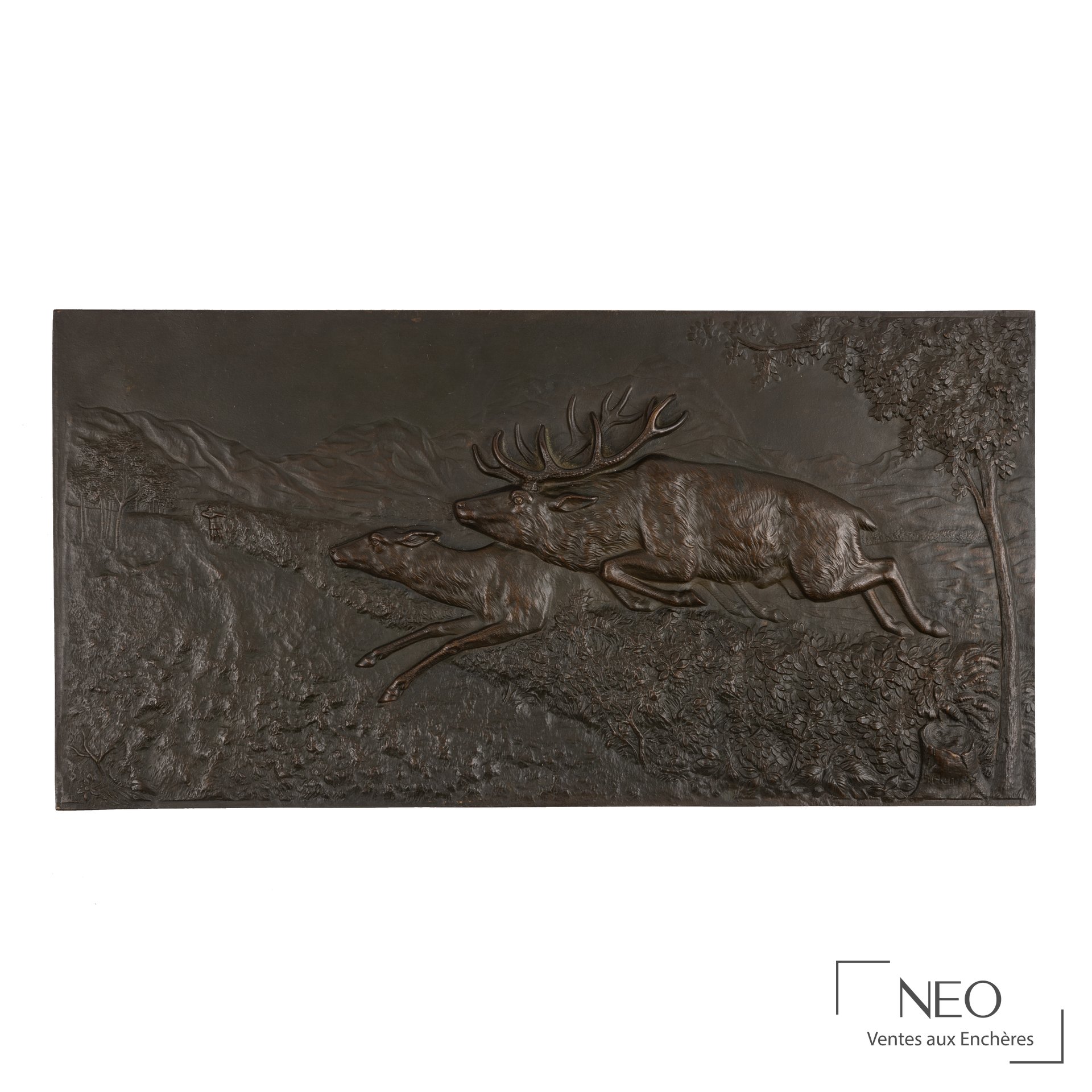 Bas-relief en bronze patiné représentant un cerf et une biche en course dans un paysage de montagne