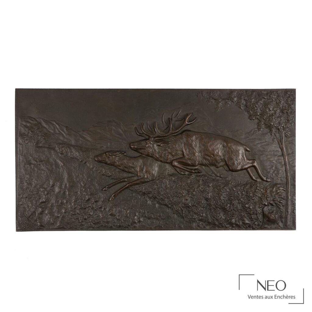 Bas-relief en bronze représentant un cerf et une biche en mouvement dans un paysage boisé