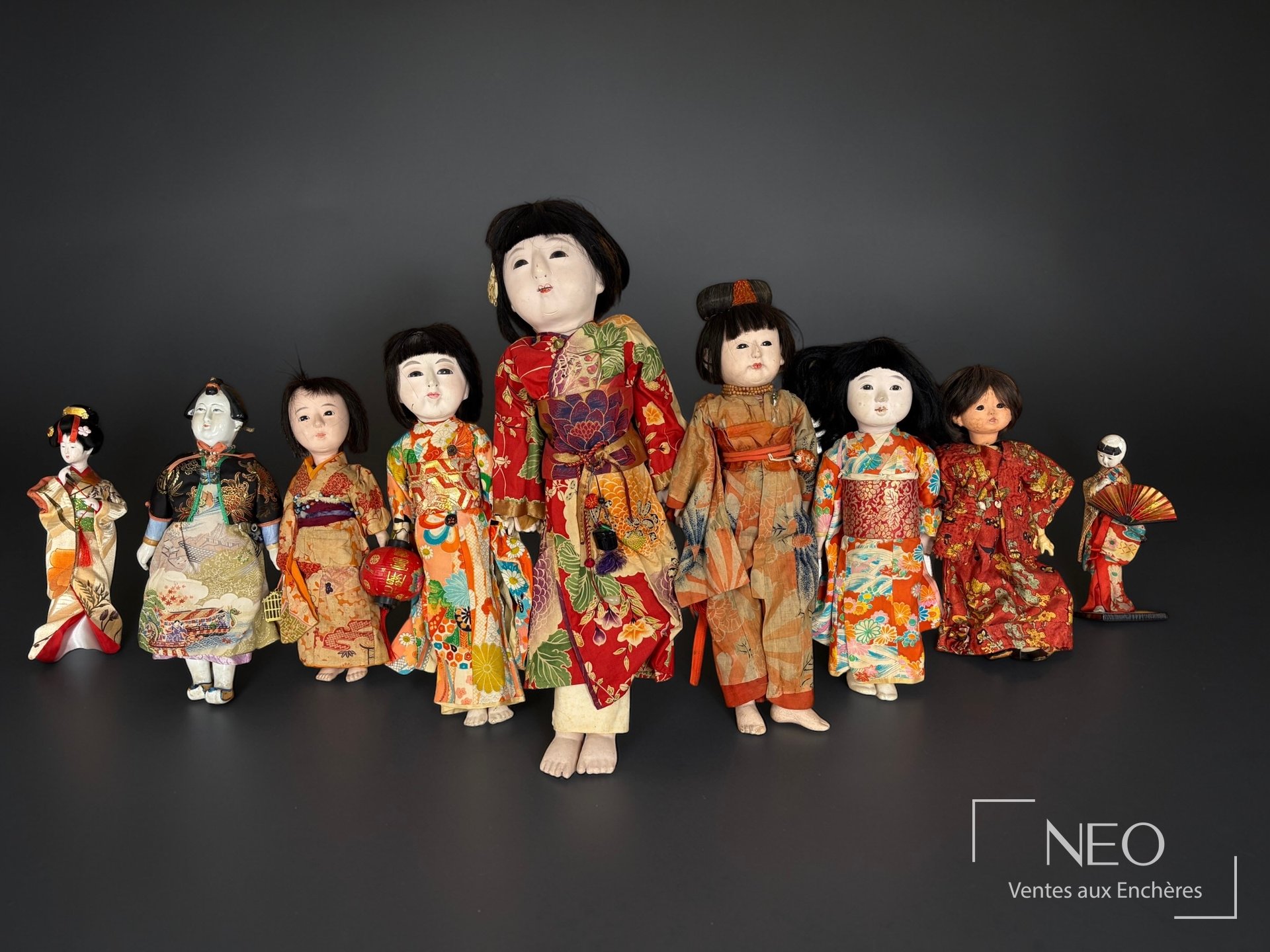 Ensemble de sept poupées japonaises vêtues de soies colorées sur fond sombre