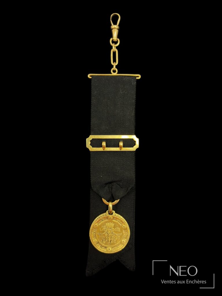Médaille en or jaune suspendue à un ruban noir avec barrette