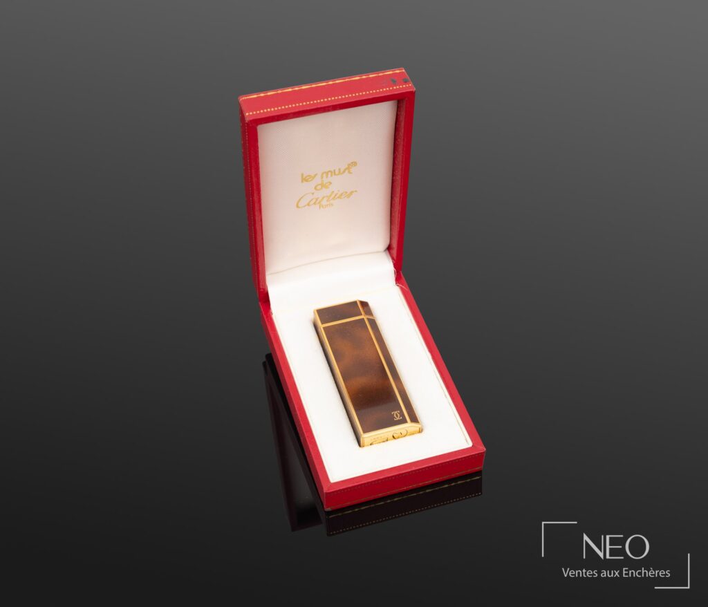 Briquet Must de Cartier présenté dans son écrin rouge et blanc