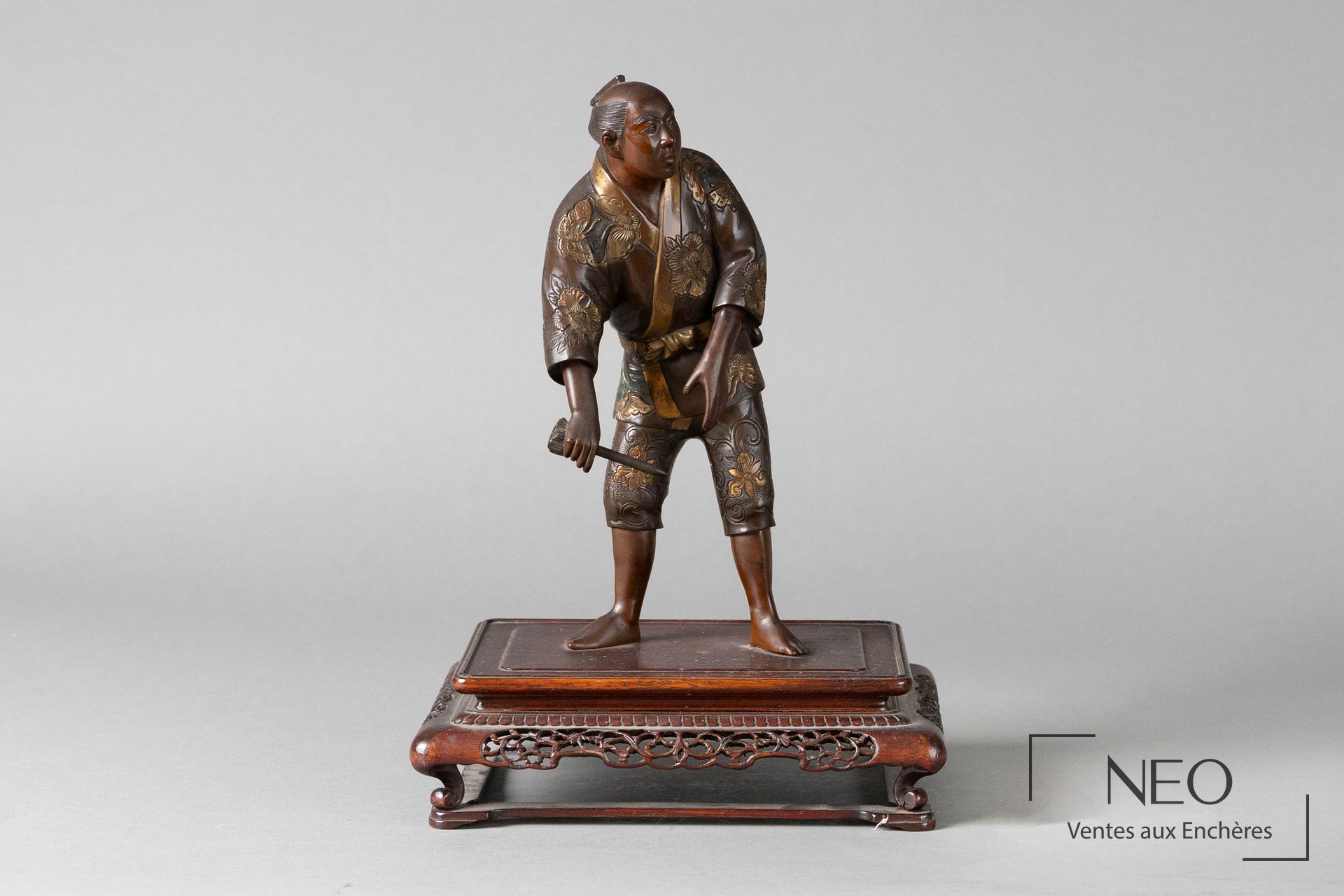 Okimono japonais en bronze représentant un homme debout sur un socle en bois ajouré