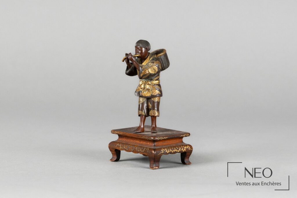 Okimono en bronze représentant un joueur de flûte sur son socle en bois décoré