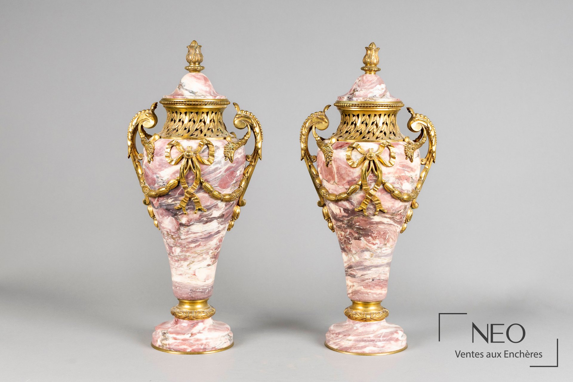 Paire de vases couverts formant garniture de cheminée en marbre veiné rose et bronze doré
