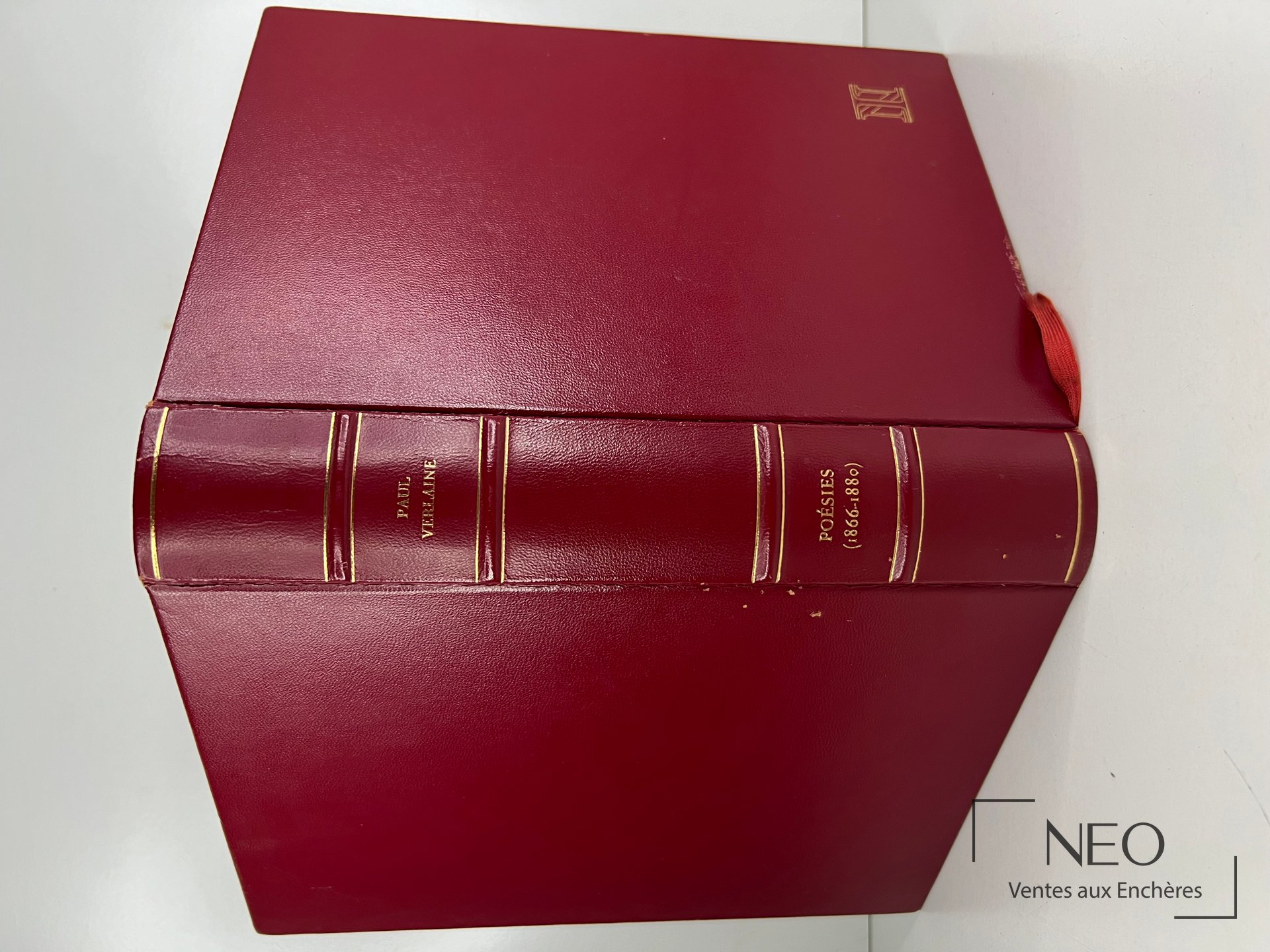 Livre relié rouge avec dos orné et ruban marque-page visible