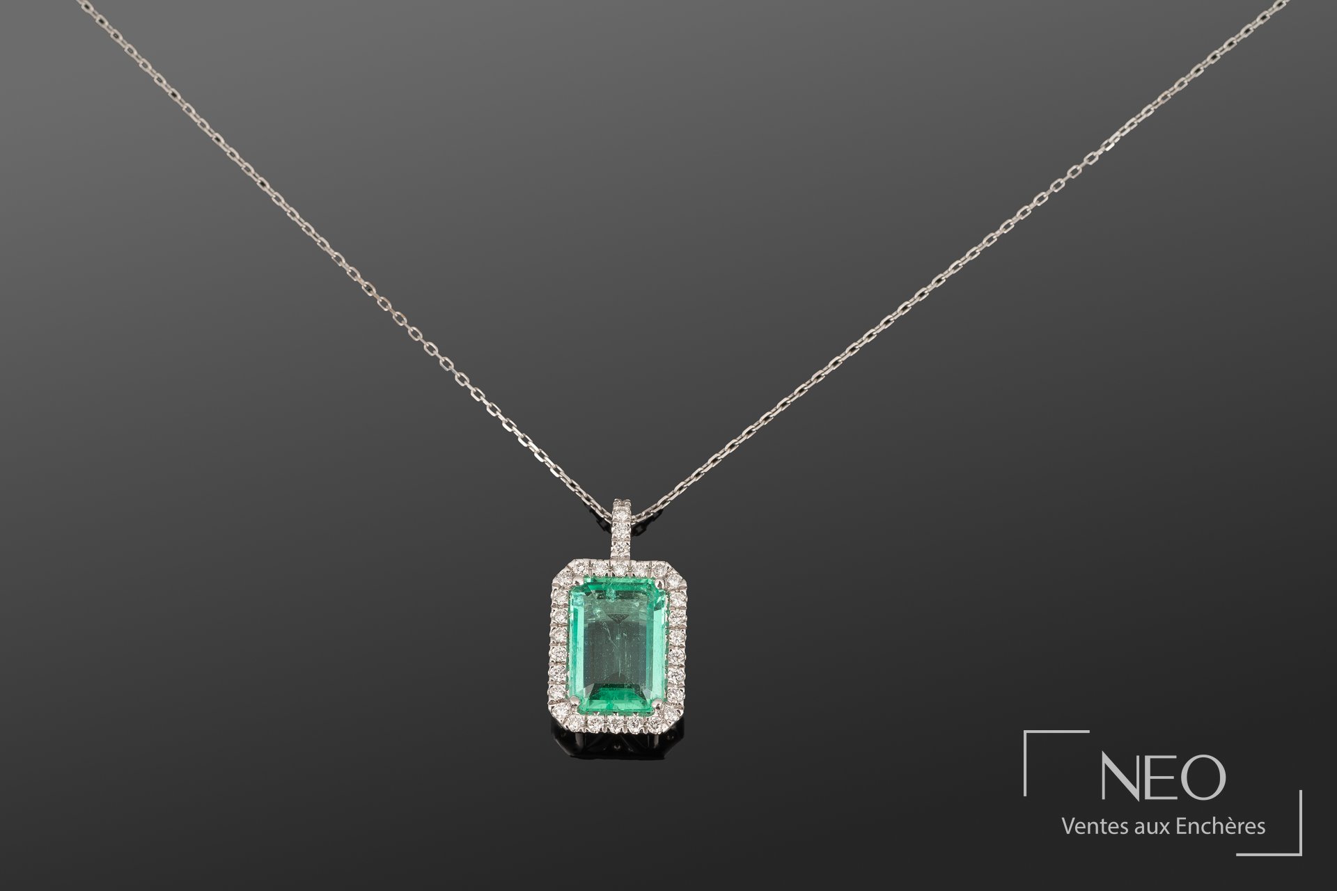 Pendentif rectangulaire en or blanc avec émeraude centrale et entourage de diamants sur chaîne fine