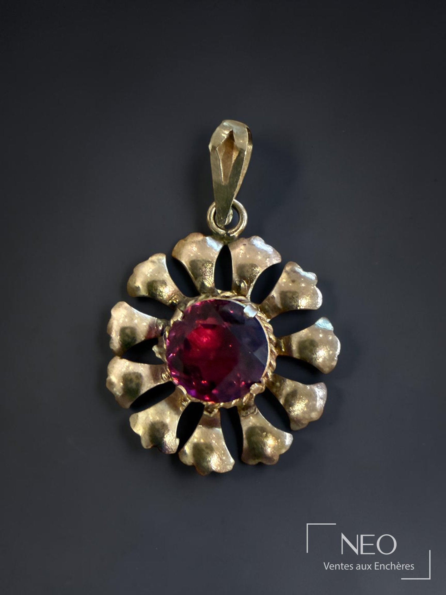 Pendentif en métal doré formant fleur à pierre rouge facettée
