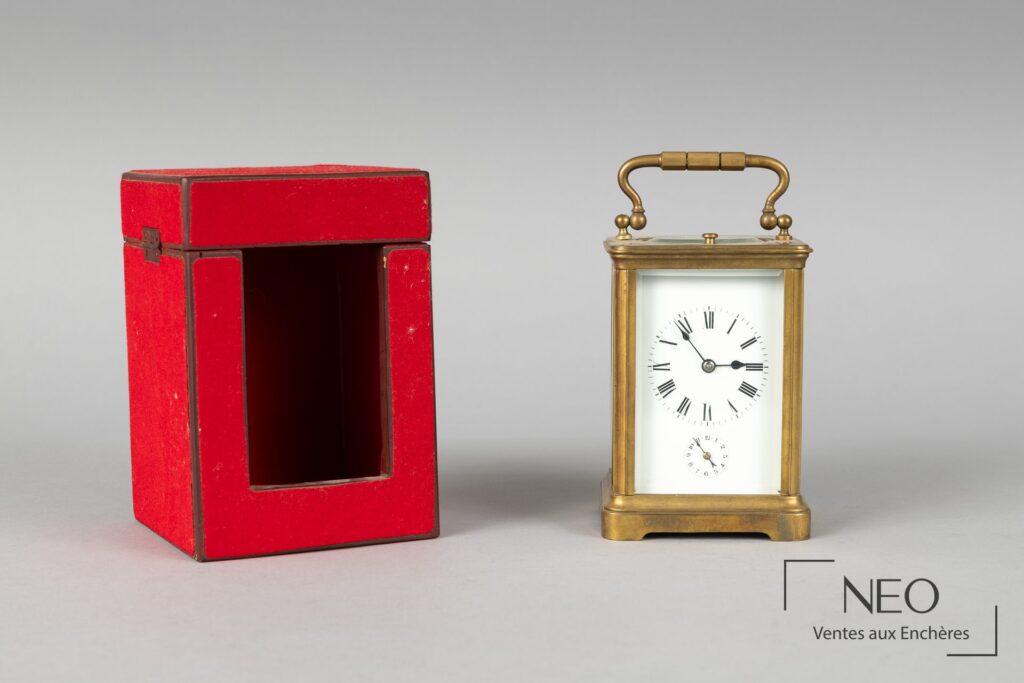 Pendule d'officier en laiton doré avec son étui rouge ouvert à côté