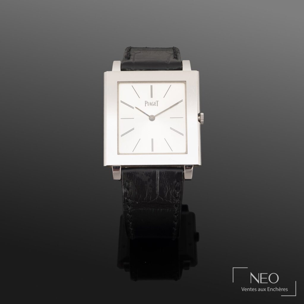 Montre Piaget carrée en or gris avec cadran argenté et bracelet cuir noir.