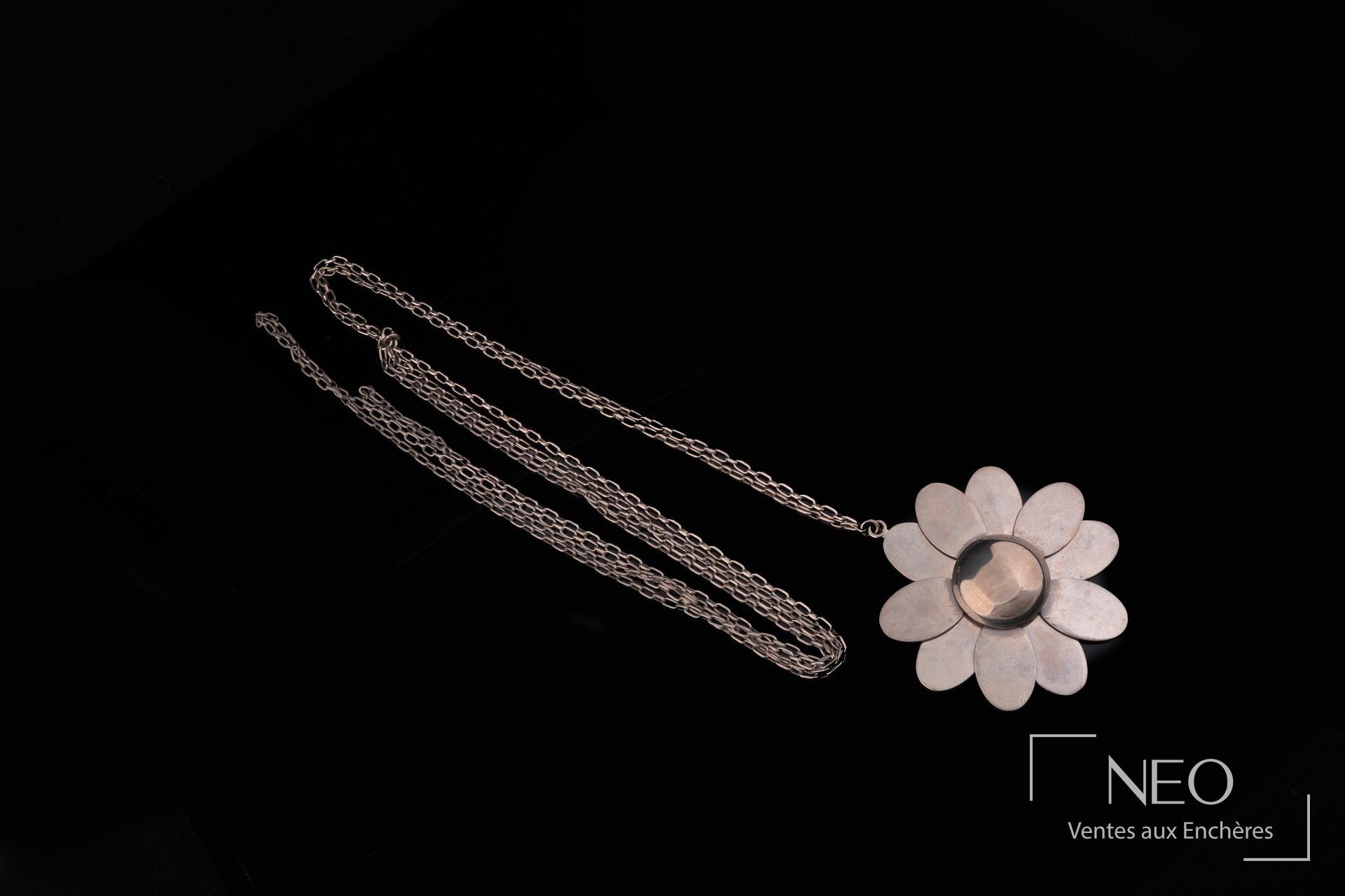 Long collier marguerite Pierre Cardin en métal argenté sur fond noir